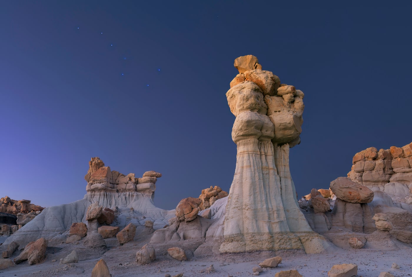 Pale sandstone hoodoos under a deep blue twilight sky in the Bisti/De-Na-Zin Wilderness, San Juan County, New Mexico