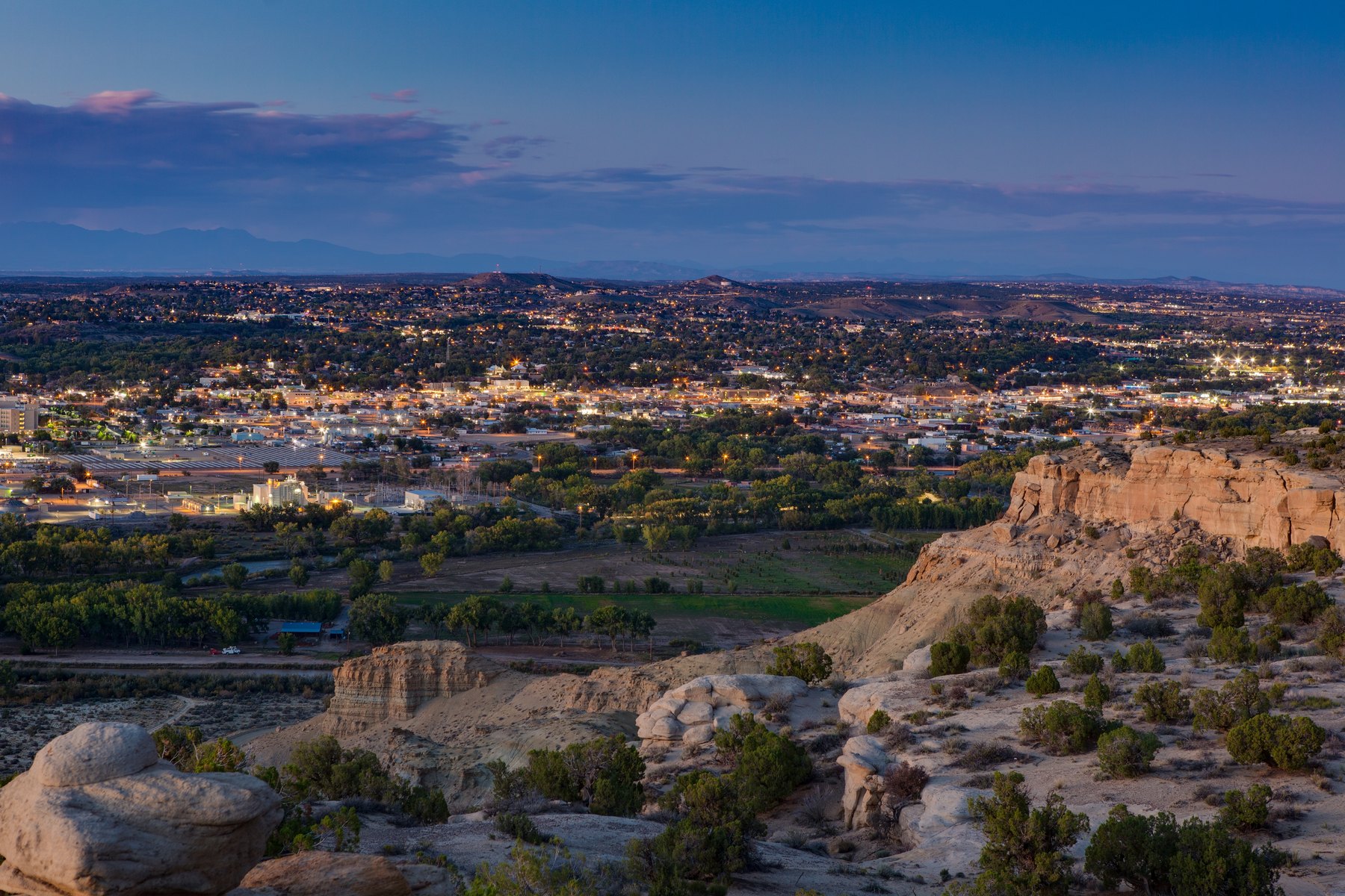 Farmington at dusk seen from sandstone bluffs, with city lights and the river valley below