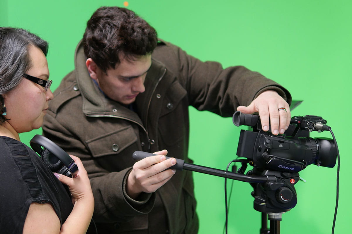 Two people working with a video camera in San Juan College’s green-screen studio