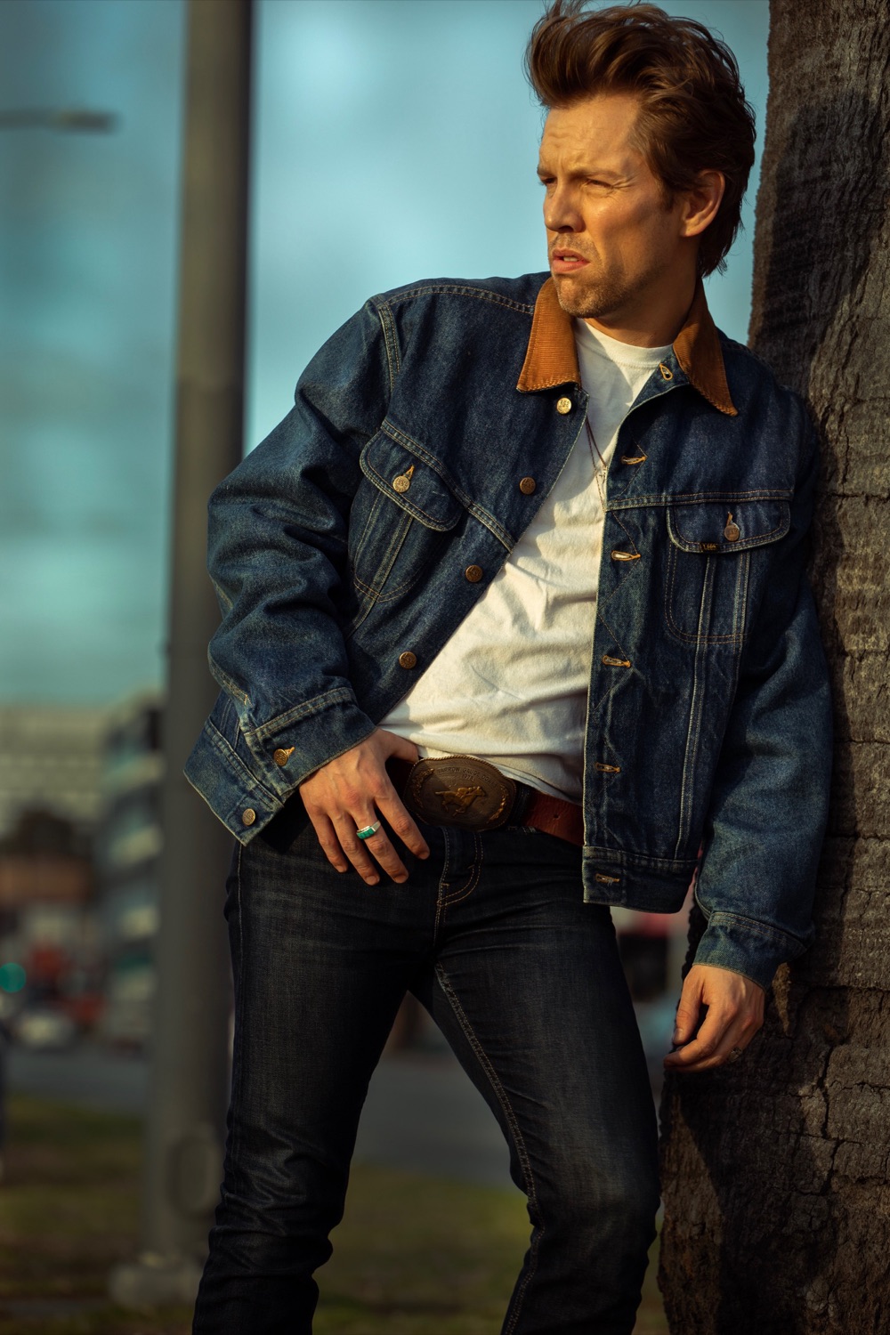 Shawn-Caulin Young in a denim jacket, standing beside a palm tree